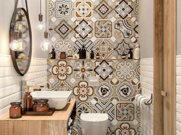 Aranżacja łazienki jest bardzo ciekawa przez wzorzyste kafle, które zdobią ścianę od góry do dołu. Wnętrze wygląda oryginalnie, a drewniane elementy, takie jak blat pod umywalką, dodają mu...