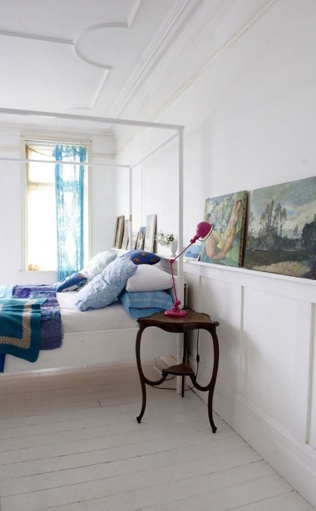 Stare obrazy i stylowe detale w aranżacji białej sypialni z niebieskimi i różowymi dekoracjami