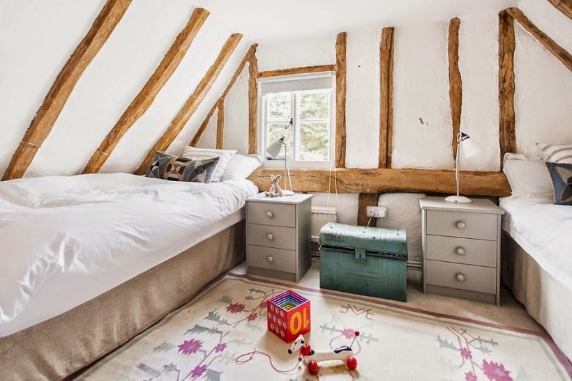 Pokój dla dzieci na wiejskim poddaszu z drewnianymi belkami,szarymi szafkami i turkusową skrzynią vintage
