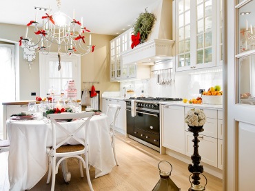 Bazowa biel w kuchni z jadalnią piękne podkreśla czerwone świąteczne dodatki, jakie zastosowano w aranżacji. Klimat potęgują większe latarenki postawione na podłodze oraz wieniec na...