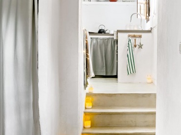 Białe wnętrza urozmaicono klimatycznymi świetlnymi dekoracjami. Wejście do kuchni zyskuje romantyczną oprawę dzięki ustawionym na schodach...