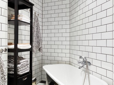 Biała glazura cegiełka na ścianie w łazience, posadzka w szachownicę ,wolnostojaca czarna wanna i czarne etażeki z pólkami (26984)
