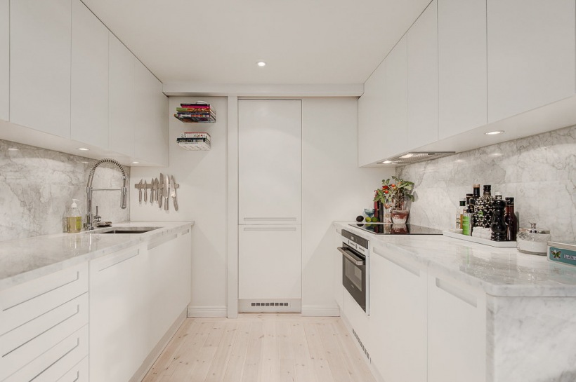 Mała biała kuchnia pod antresolą w otwartej zabudowie mieszkania