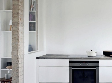 Minimalistyczna aranżacja białej kuchni z surową cegłą i betonową posadzką (21291)