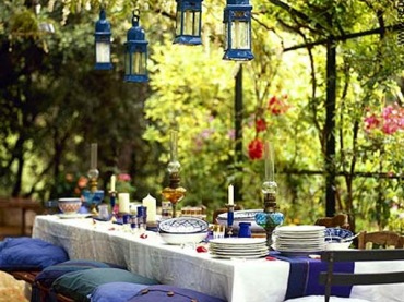 Niebieskie lataraenki, poduchy i dodatki w aranżacji biesiadnego stołu w letnim ogrodzie (25408)