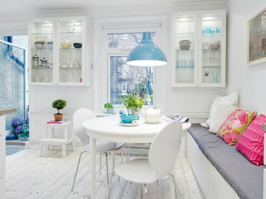 Wiszące białe witrynki, okrągły stół i ławka z poduszkami w skandynawskiej jadalni z niebieską lampą (22024)