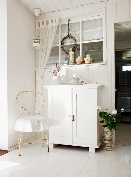 Metalowe białe krzesło francuskie z patyną,biała komoda,latarenka i koronkowo-woalowe firanki w przeszklonej ściance
