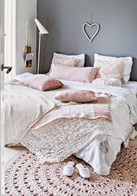 Szara ściana w sypialni z różowymi i pastelowymi dodatkami,dziergany dywanik okragły