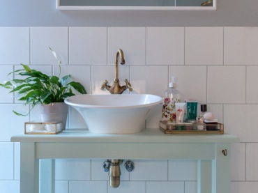 Biało-szara łazienka prezentuje się lekko i inspirująco. Do białej umywalki w kształcie misy dobrano złoty kran, który...