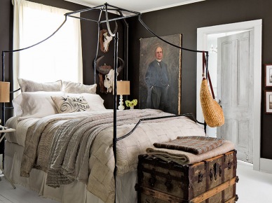 ciemnoszara sypialnia dobrze prezentuje się z białą podłogą i kutym, czarnym łóżkiem. Dekoracje w bieli i drewniany kufer nadają jej uroku pokoju wielkiego...