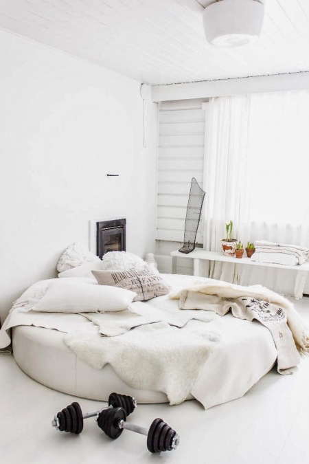 Okrągłe łóżko w aranżacji białej sypialni z postarzanymi detalami