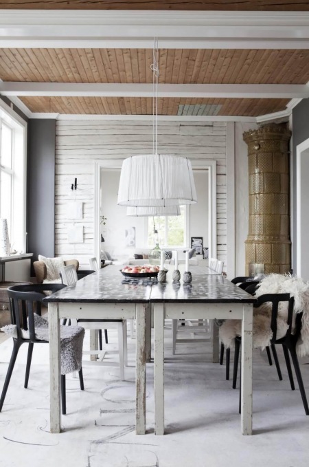 Biały stół z czarnym blatem,czarne skandynawskie krzesła,biała lampa wiszaca,drewniany sufit z białymi belkami w jadalni