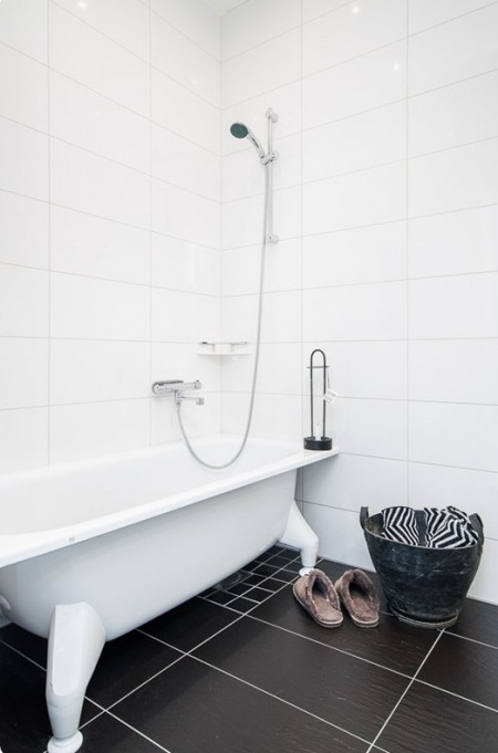 Aranżacja białej łazienki z wanną na łapkach i czarną terakotą na podłodze