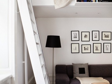 Mini antresola z półkami na książki i białą drabiną nad grafitową sofą w salonie (27649)