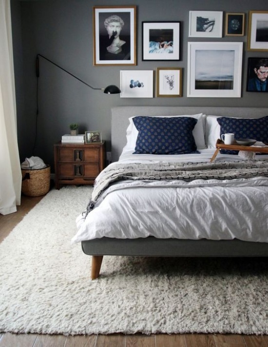 Aranżacja sypialni z szarym łóżkiem i drewnianą szafą nocną
