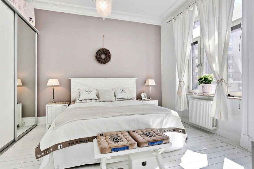 Białe drewniane łóżko,białe dekoracyjne zasłony i szara ściana w sypialni