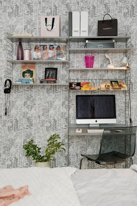 Graficzna skandynawska tapeta na ścianie z metalowymi ażurowymi pólkami w kąciku domowego biura