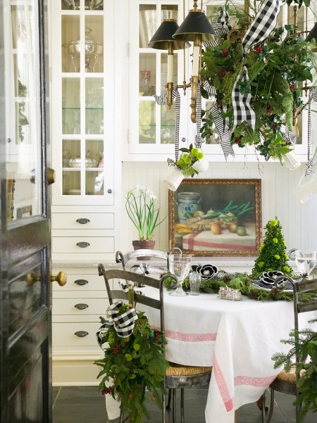 Biała kuchnia tradycyjna z okragłym stołem i kutymi metalowymi krzesłami w światecznej zielonej dekoracji