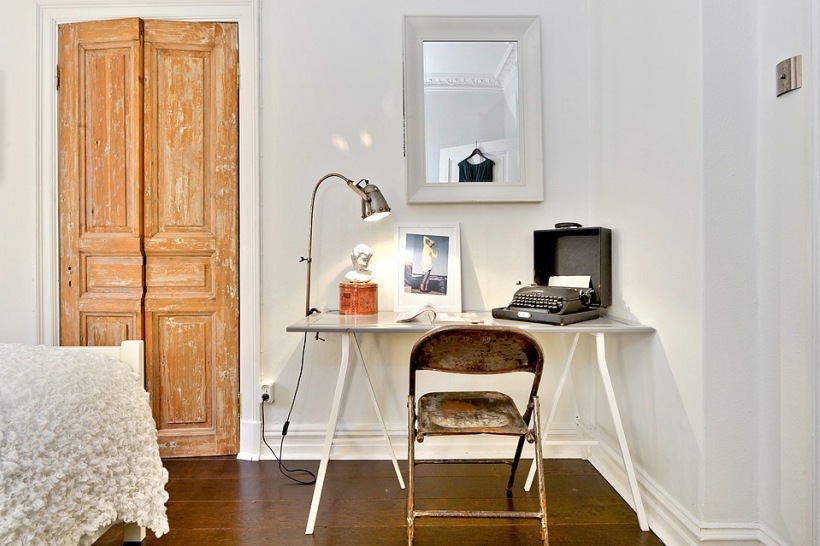 Nowoczesne biurko z metalowym krzesłem vintage i drewniane postarzane drzwi w skandynawskiej sypialni