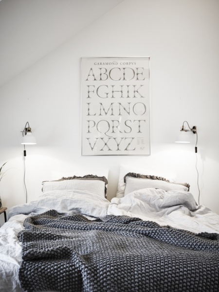 Sypialnia skandynawska z typografią i kinkietami nad łóżkiem