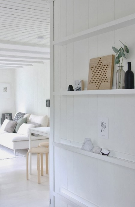 Biała boazeria z pólkami na ścianie w skandynawskim domku