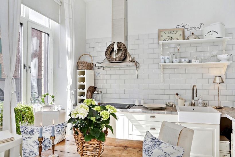 Wiklina,drewniany stół i wiszące białe półki w skandynawskiej kuchni