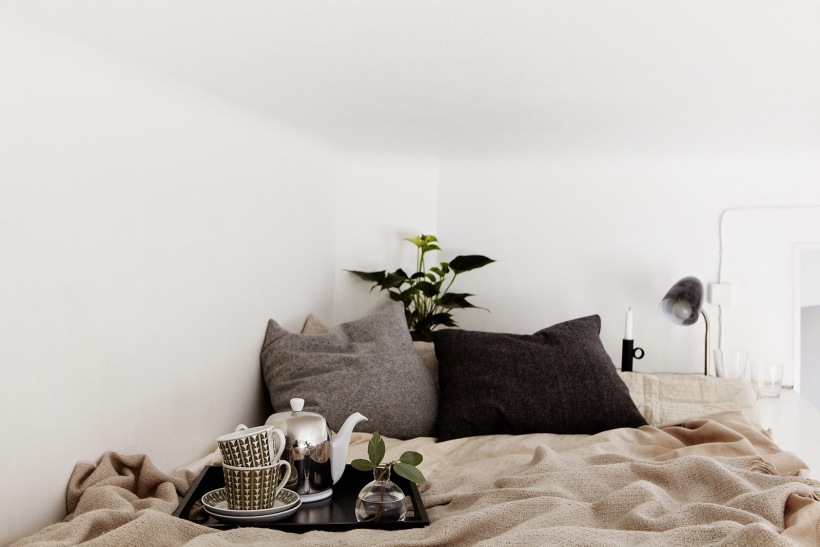 Szare i czarne poduszki, beżowa narzuta na łóżku na małej antresoli