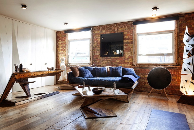 Oryginalne i dizajnerskie meble z drewna w salonie ze ścianami z czerwonej cegły