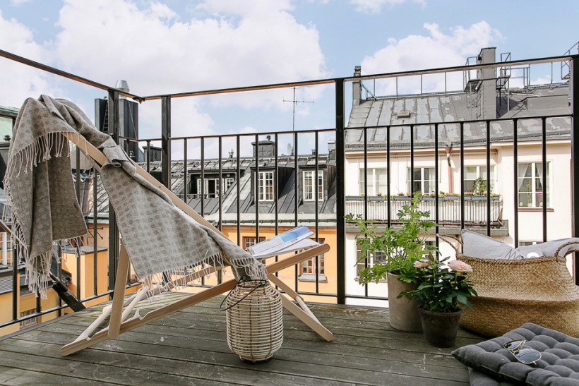 Skandynawska letnia aranżacja małego balkonu z leżakiem,koszem z trawy morskiej i nastrojową latarenką