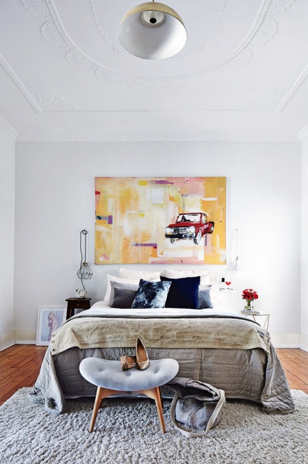 Białe sztukaterie na ścianach,nowoczesny obraz,industrialna lampka,szara narzuta i czarne i szare poduszki na łóżku