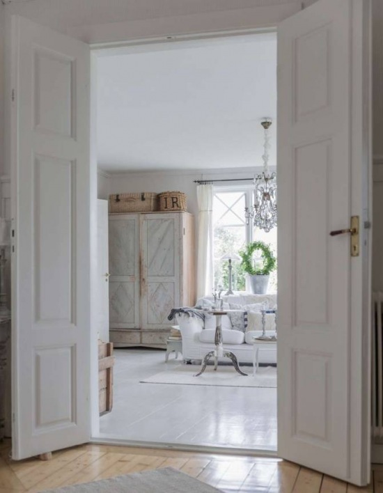 Drewniane drzwi i podłogi w białym salonie