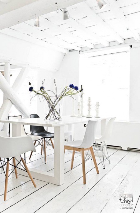 Biały stół, krzesła i bielone drewno na ścianach i podłodze