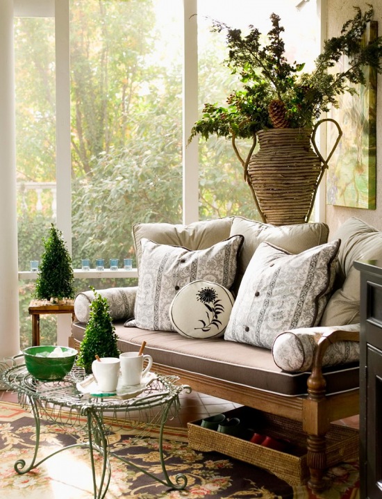 Wyplatany wazon z bukietami,kuty turkusowy stolik pomocniczy,stylowa drewniana kanapa z poduchami i zielone małe choinki świąteczne