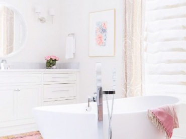 W białej łazience bardzo ładnie prezentują się dodatki w kolorze pastelowego różu. Kubełkowa wanna na środku dodaje...