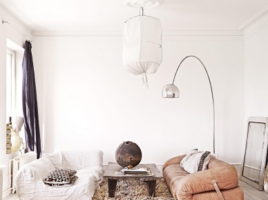 Lampa kokon z drutu i bawełny,skórzana sofa desingerska z zapięciami bocznymi,dywan futrzak,lampa podłogowa srebrna i gliniany wazon na drewnianej ławie (27390)