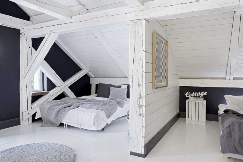 Białe drewniane belki i szare ściany w sypialni na poddaszu