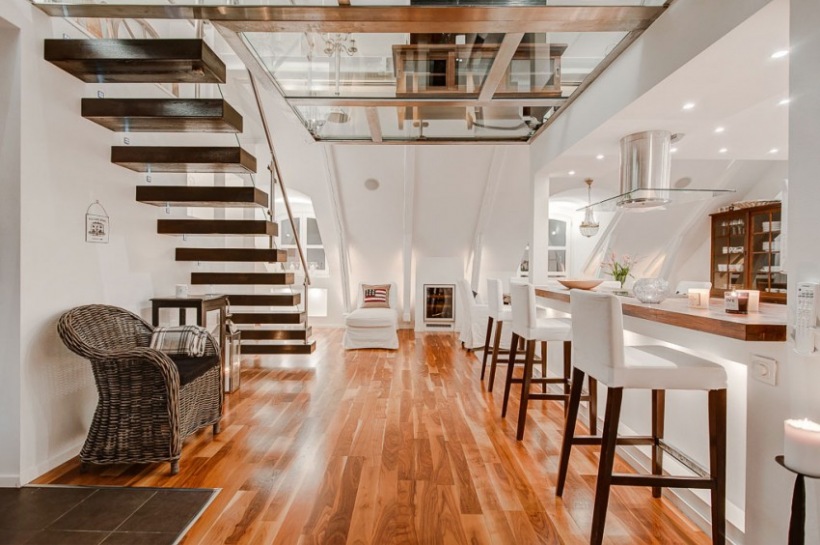 Szkło, drewniane nowoczesne schody i wiklina w otwartej aranżacji kuchni na poddaszu