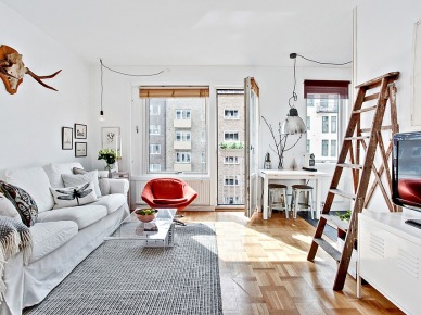 Aranżacja białego salonu skandynawskiego z drabiną,porożem jelonka i czerwonym fotelem (23537)