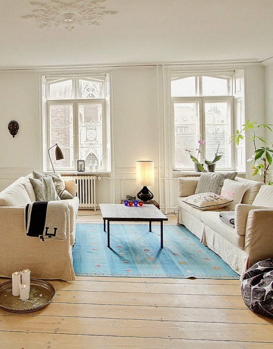 Nowoczesne obrazy,naturalne drewno,tkane dywany i proste witryny w skandynawskim salonie