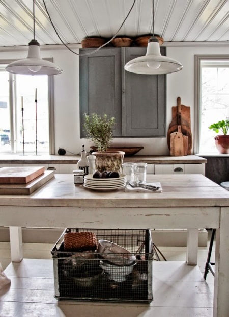 Białe metalowe lampy wiszące nad drewnianym stołem vintage,szara szafka kuchenna,drewniane deski deserowe i druciana metalowa skrzynka industrialna