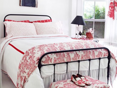 Czarne kute łóżko,czerwony puf i stylowa biało-czerwona pościel w wiejskiej sypialni (24399)
