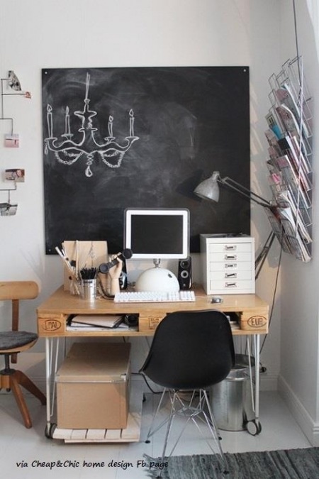 Biurko z drewnianej palety na metalowych nóżkach i ściana z tablicową czarna farbą w dekoracji domowego biura