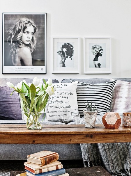 Dekoracja szarej sofy poduszkami w biało-czarne wzory i skandynawskie grafiki i fotografie na ścianie w salonie