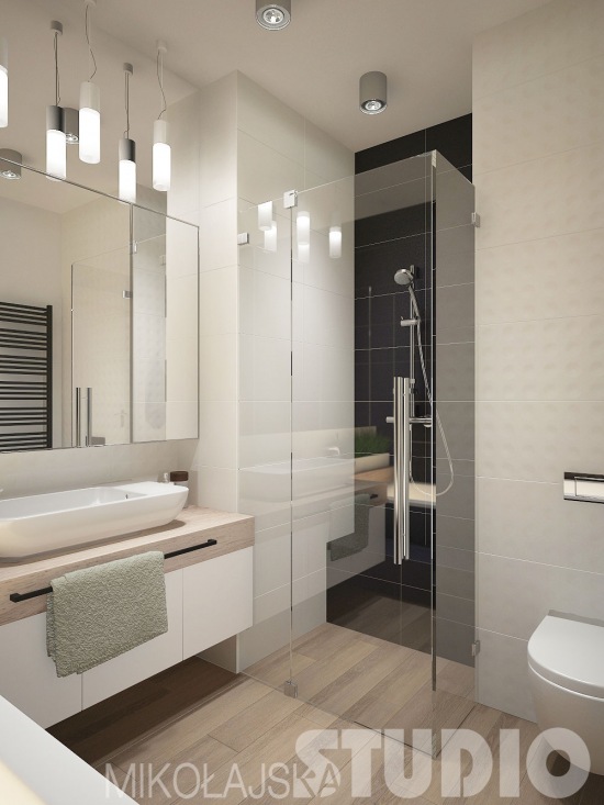 Funkcjonalna łazienka z lustrzaną ścianą,szklaną kabina we wnęce i białymi szafkami z detalami z drewna