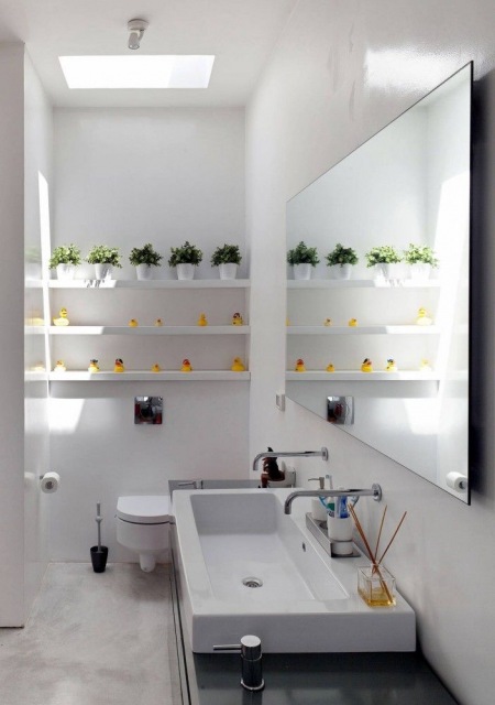 Białe półeczki na ścianie w łazience z długą prostokatną umywalką na czarnym blacie szafki,długie prostokatne lustro bez ram nad umywalką