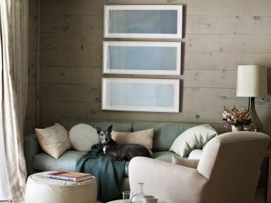 Szaro-beżowe deski na ścianie i podłodze,mietowa sofa,szmaragdowy pled i biały okrągły puf w salonie (25341)