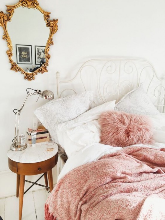 Aranżacja białej sypialni ze złotym lustrem i różowymi dodatkami