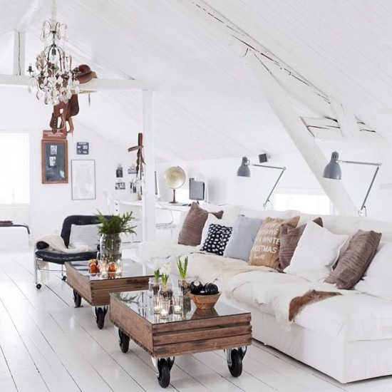 Biału loft z drewnianymi skrzynkami na kółkach ,kryształowym żyrandolem i kinkietami