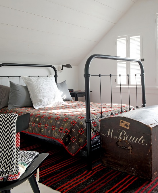 Metalowe kute łóżko,patchowrkowa narzuta i kolonialny kufer skrzynia w sypialni