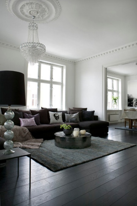 Czarna sofa pośród kryształów i srebra w białym salonie